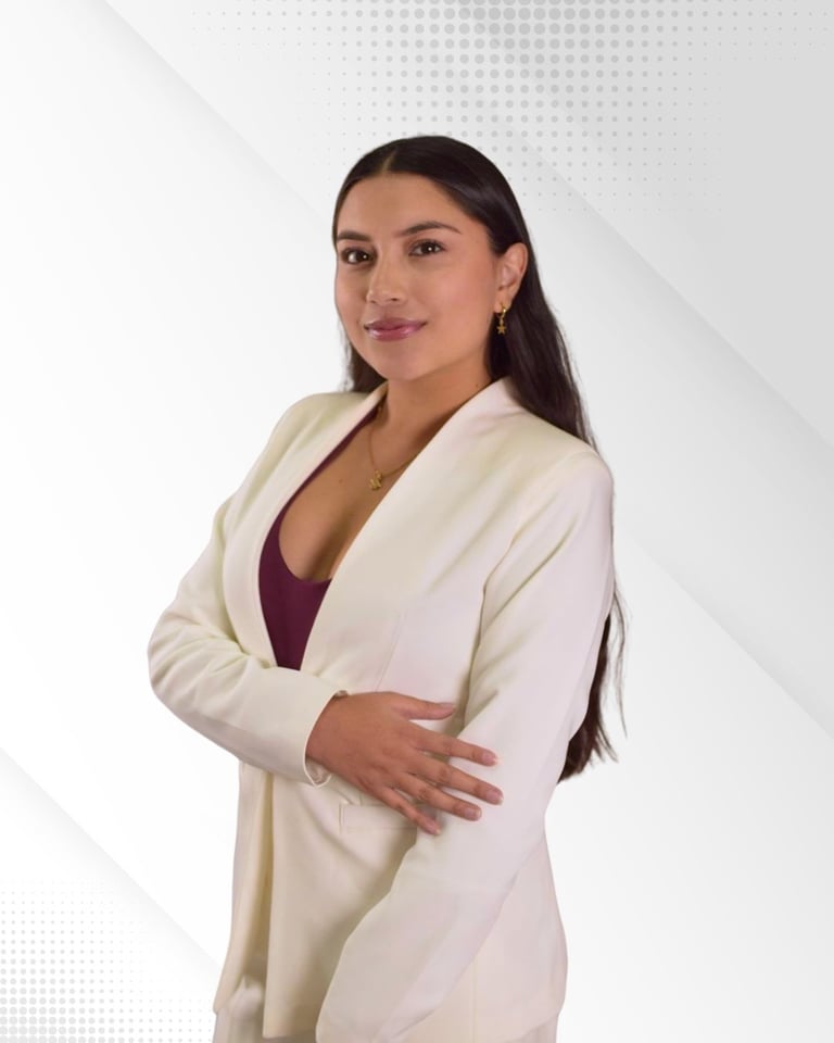 Professional woman with dark hair wearing a cream-colored blazer over a burgundy top, posing with arms crossed against a light background